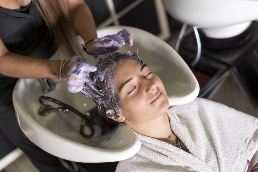 Female with eyes closed and head back in sink having hair shampood