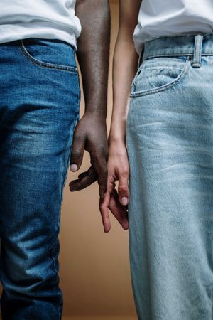 Two people in denim pants touching hands