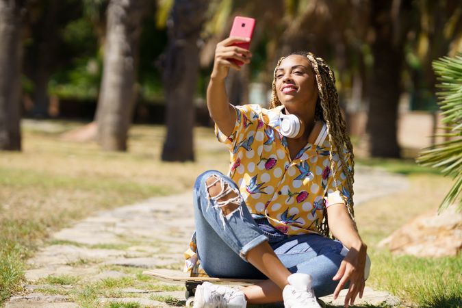 Female in bold patterned shirt taking selfie in park