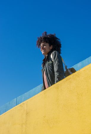 Black woman with afro hair leaning against brightly colored walls.