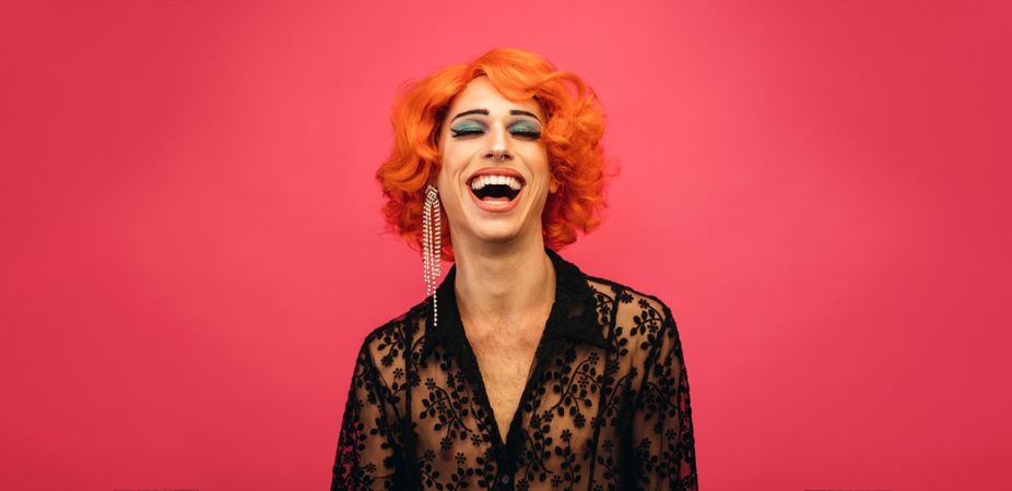 Portrait of drag queen laughing on red background