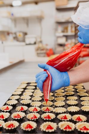Crop baker filling pastry cases with jelly