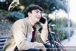 Smiling man using mobile phone while sitting outdoors 4d88Ln
