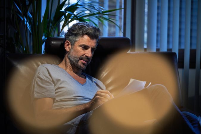 Bearded businessman writing notes in dark room
