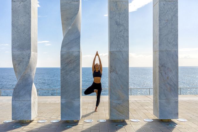 Female standing on one leg between sculpture with ocean view 