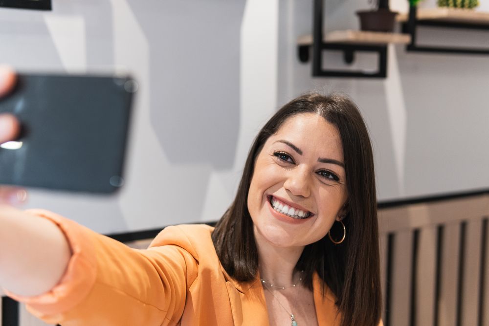 Cheerful woman taking selfie on smartphone in cafe