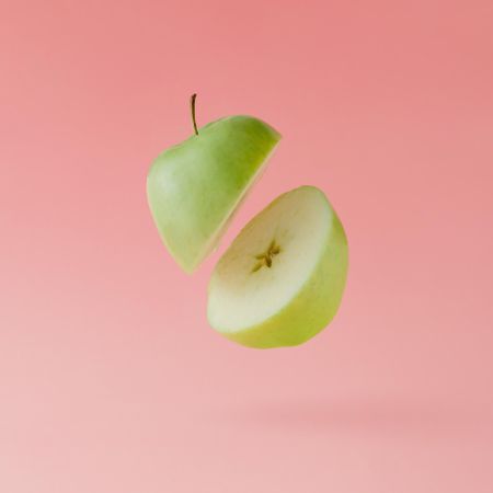 Apple halved on pastel pink background