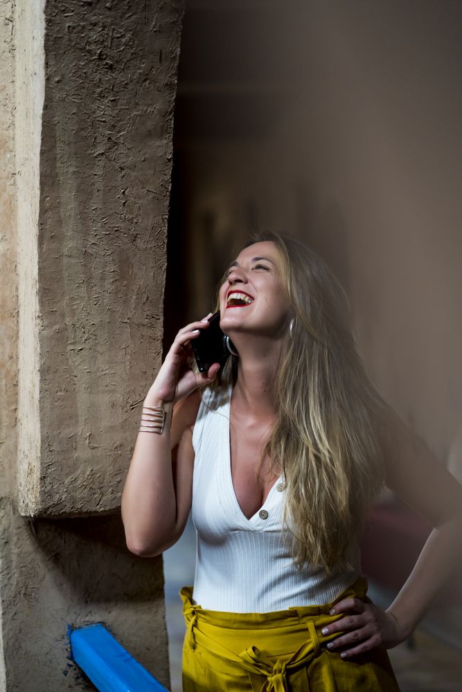Smiling woman using smartphone on old balcony