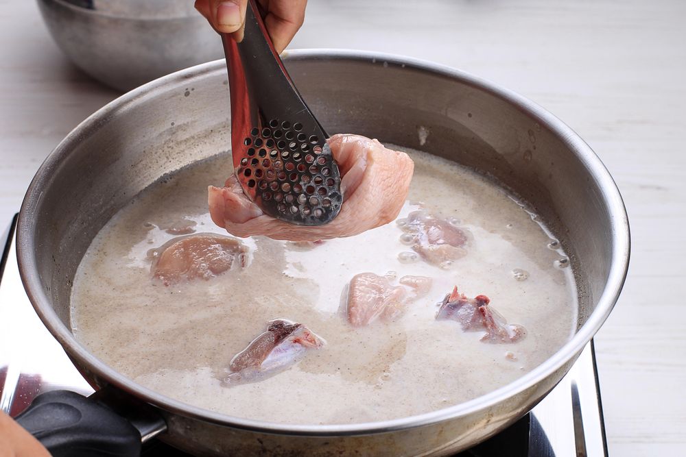 Female Hand Add Chicken Thigh Drumstick to the Pan using Tongs, Making Indonesian or Thai Style Curry