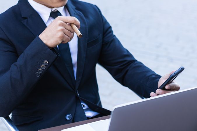 Businessman smoking cigar in street cafe