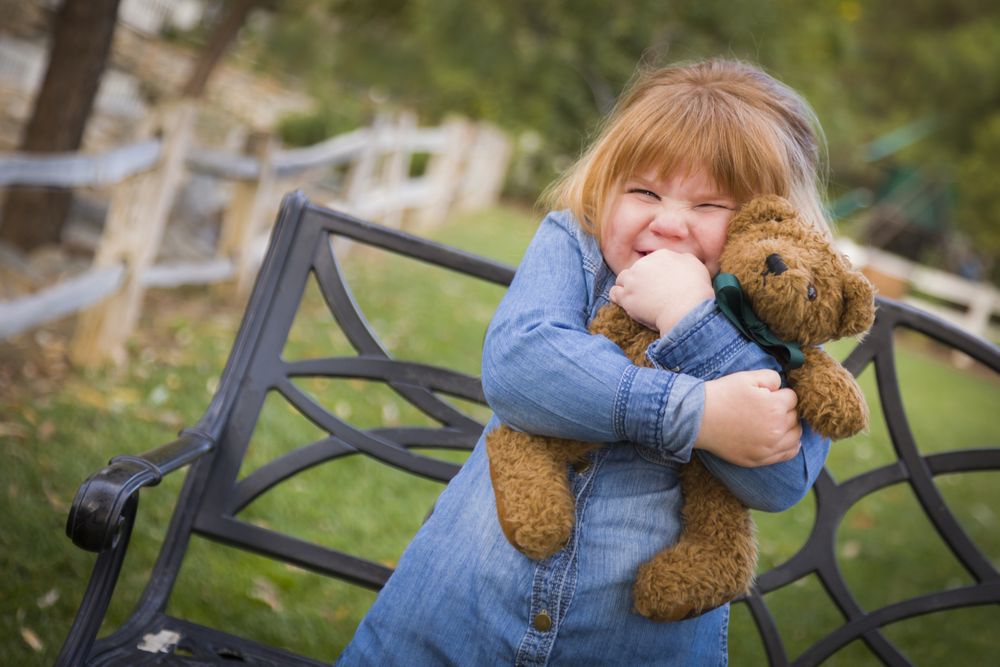 Cute Smiling Young Girl Hugging Her Teddy Bear Outside