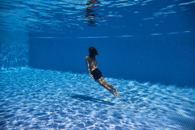 Boy swimming towards surface of tiled pool