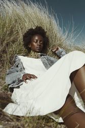 Woman in light dress and denim jacket laying on brown grass