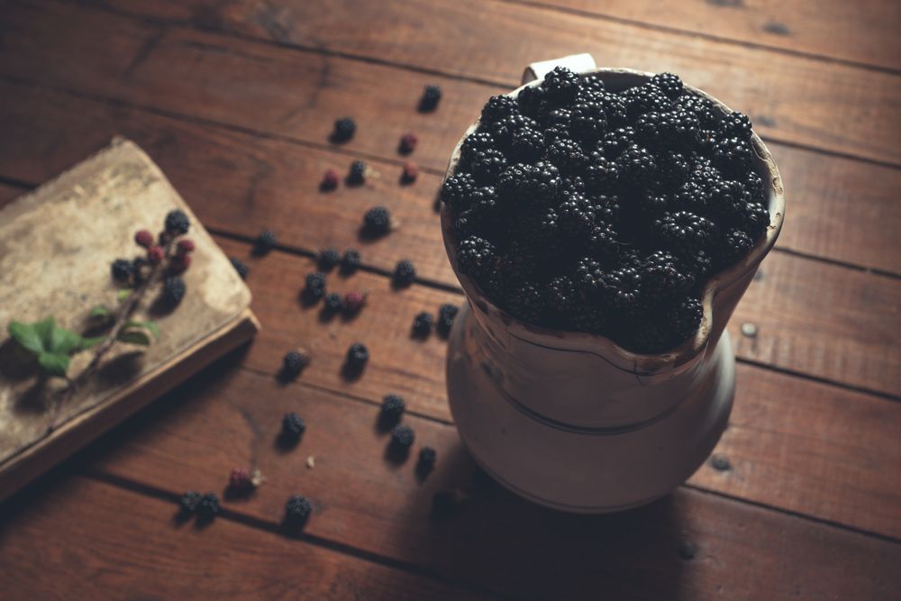 Vintage jag with ripe blackberries on wood