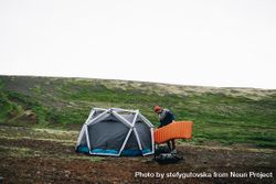 Man setting up tent in a green field 48PeY4