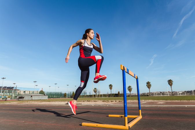 Female athlete hurdling on stadium