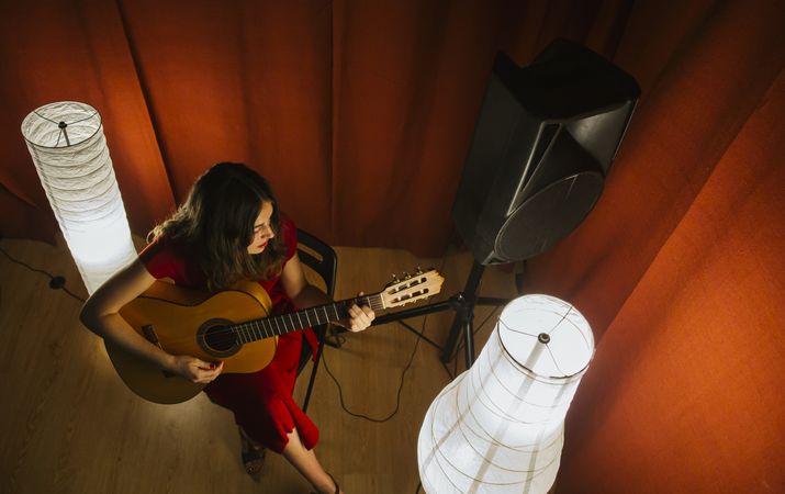Woman singing and playing guitar on stage in lamplight
