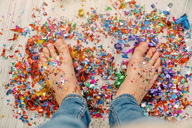 Boy standing on colorful confetti during party