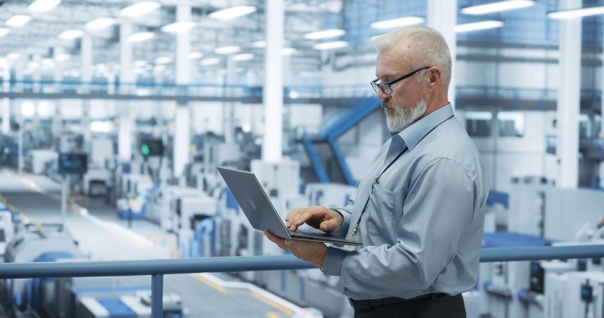 Electronics Manufacturing Technician Working on a Laptop Computer at a Factory Space. Specialist Developing, Maintaining, Fine-Tuning Programs for Machine Production and Assembly