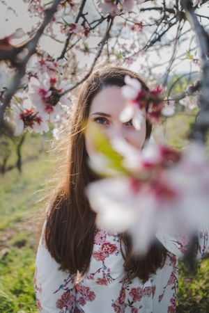 Young happy woman between trees in garden