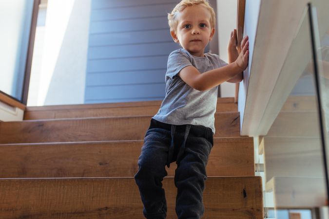 Little boy walking down stairs taking support of a wall