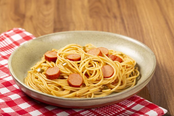 spaghetti pasta with sliced sausages and tomato sauce.