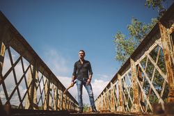 Man with guitar standing on bridge
