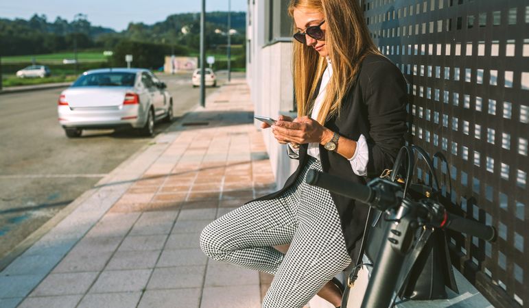 Businesswoman with mobile and her scooter next