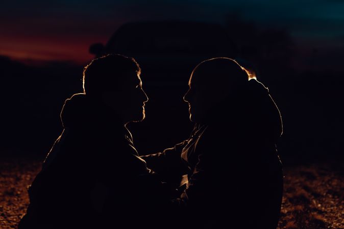 Men hugging and sitting on ground on field at night