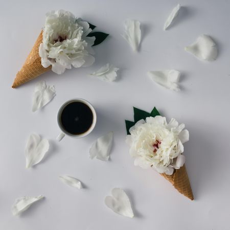 Coffee cup with flowers, ice cream cones and petals