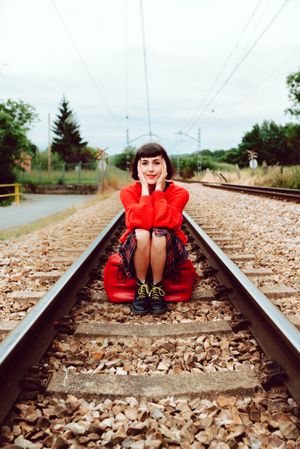 Woman sitting on sleepers in middle of railway