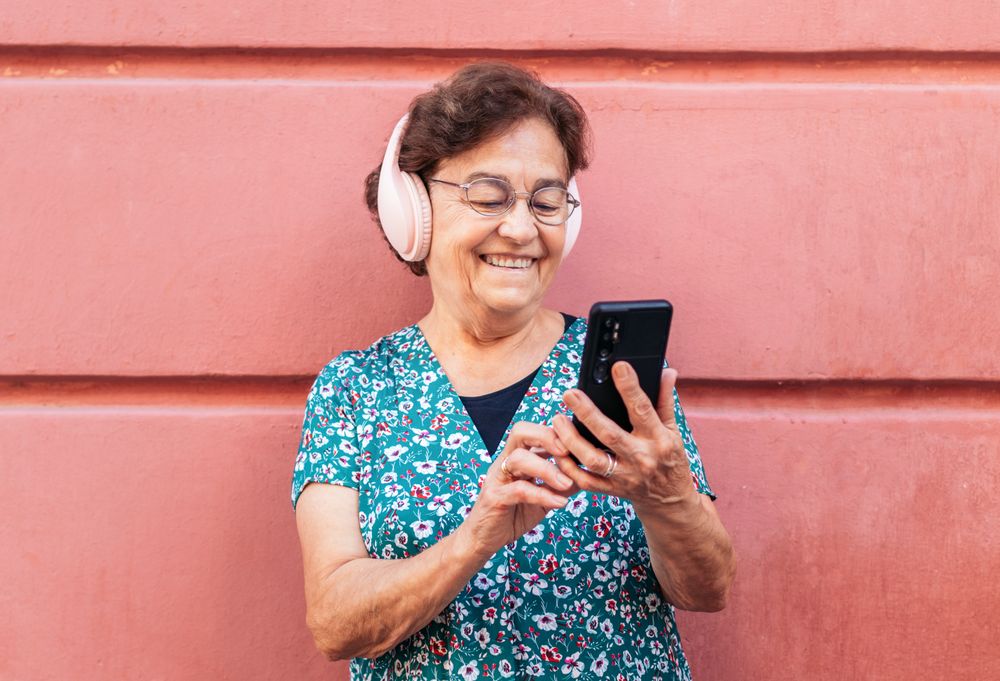 Older woman using smartphone and listening to music with headphones