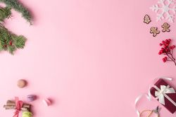 Winter Christmas table layout with presents, decorations, branches on pastel pink background