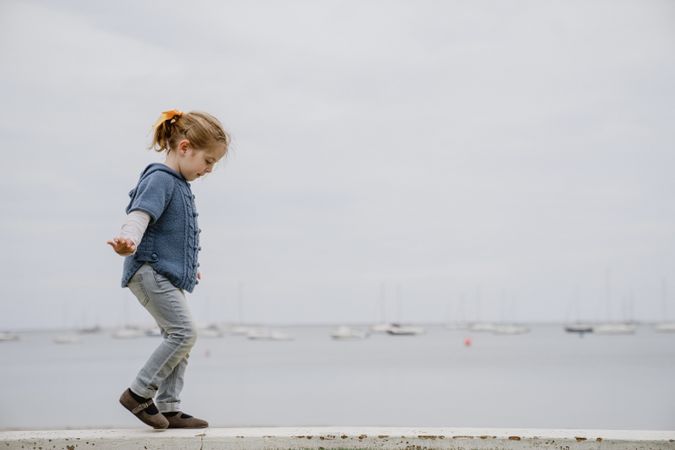 Girl balancing on border near sea