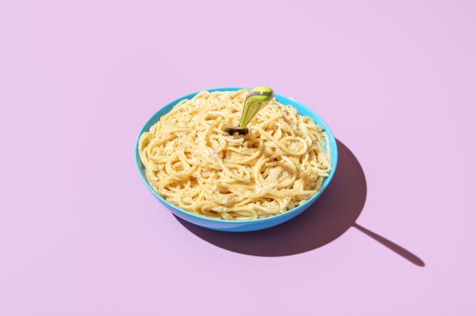 Creamy spaghetti bowl isolated on a purple background
