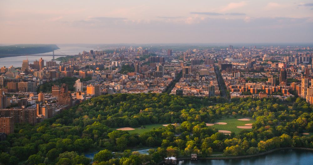 New York Cityscape at Sunset. Aerial Shot from a Helicopter. Modern Skyscraper Buildings Around Central Park in Manhattan Island. Focus on Nature, Trees and Lakes in the Park in the City