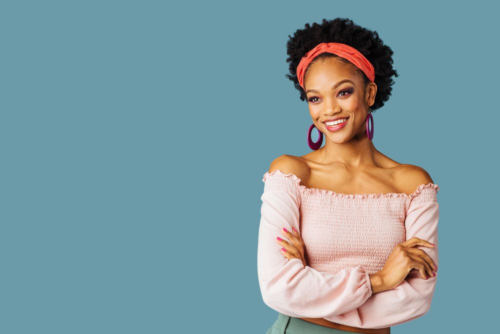 Studio shoot of smiling Black woman with her arms crossed