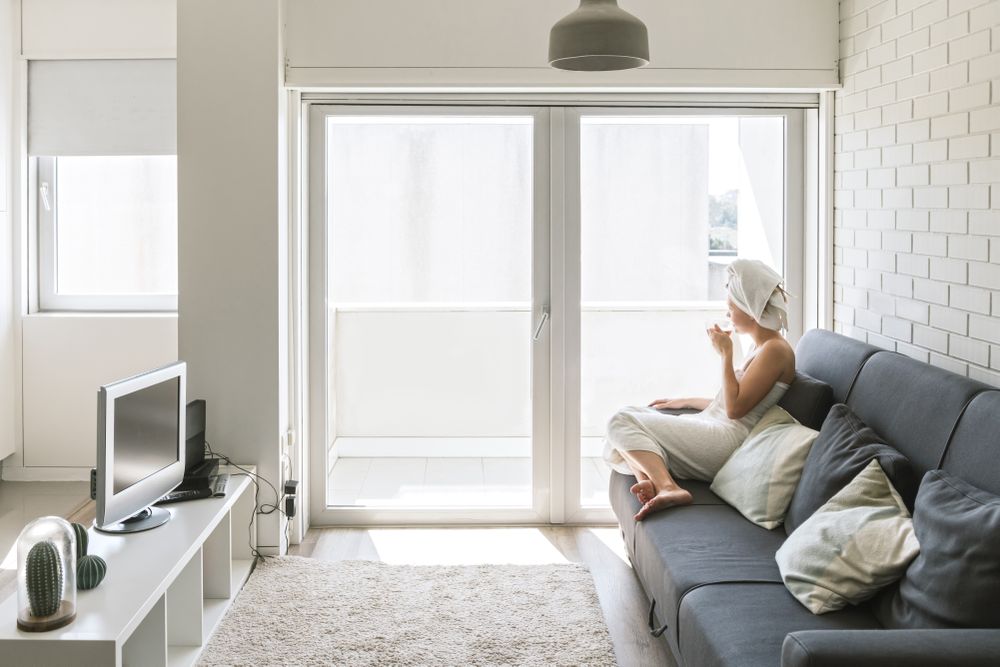 Adult relaxed woman enjoying life while resting on sofa and having hot drink after shower in own cozy apartment