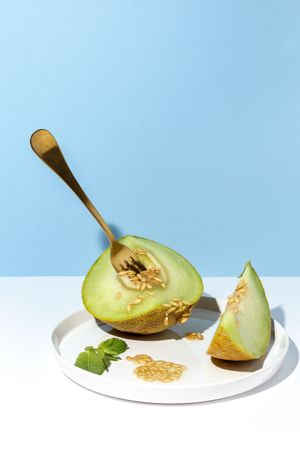 Sliced small melon on plate with spoon and fork