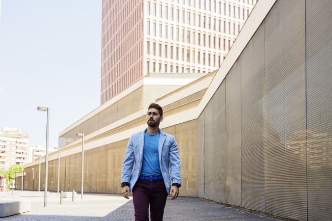 Young bearded man in blazer walking on the street