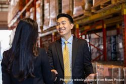 Smiling Asian professional male shaking hands of female colleague 5XBXGb