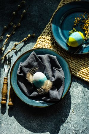 Top view of Easter holiday table setting with Easter egg & feather