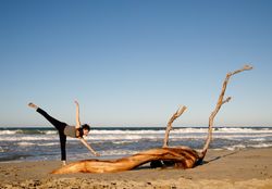 Young woman dancing and posing near water on shore