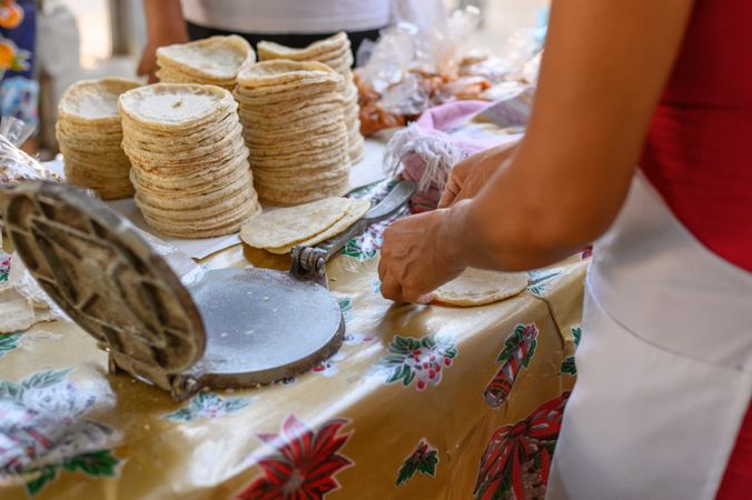 Crop cook making tortilla with press machine at stall