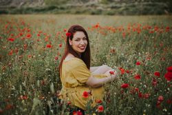 Woman sitting in field with poppies and daisies