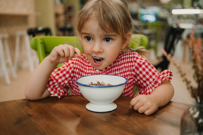 Girl eating with hand from white bowl