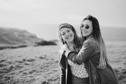 Stylish cheerful women standing on green field