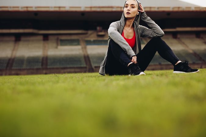 Female athlete sitting on ground and relaxing after workout