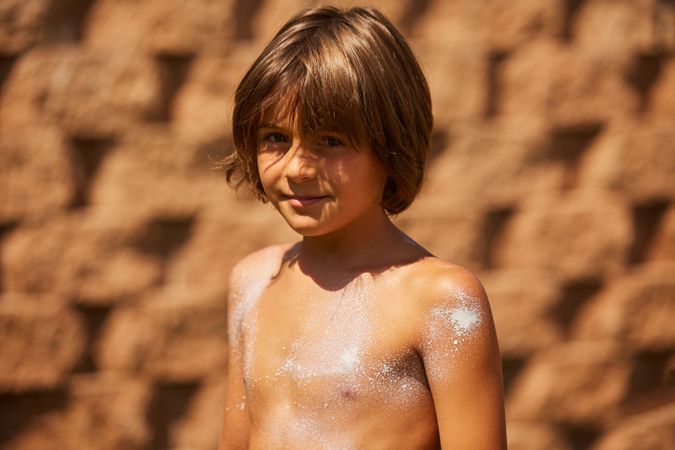 Boy with sunscreen on the body looking at the camera