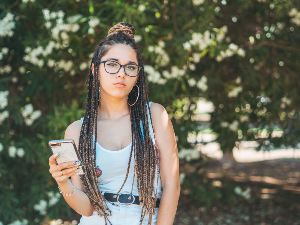 Trendy young female using mobile phone outside